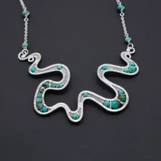 Wire wrapped silver necklace with turquoise gemstones .