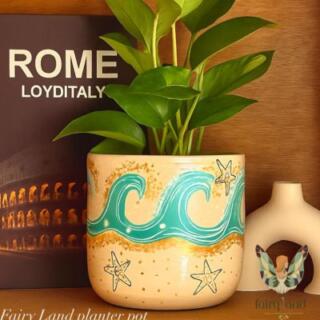 أصيص زرع فخار كبير مرسوم عليه أمواج بحر زرقاء ونجوم بحر ذهبية.| Large clay planter featuring hand-painted blue sea waves and golden starfish.