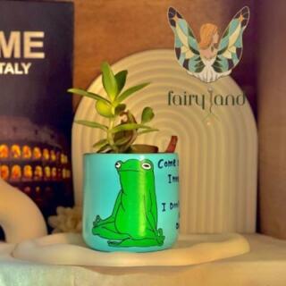 أصيص زرع فخاري أزرق عليه رسمة ضفدع يمارس اليوغا مع نبات صبار صغير | Blue ceramic planter with a meditating frog illustration and a small succulent