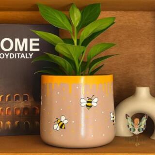 AR: أصيص زرع فخاري بلون بيج مزين برسم يدوي لنحل وعسل يقطر من الأعلى | Beige ceramic planter decorated with hand-painted bees and dripping honey design.