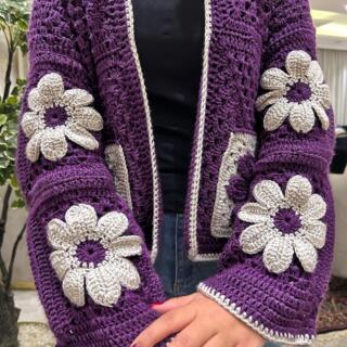 Handmade crochet cardigan in deep purple with large cream and purple 3D floral granny-square details and contrasting trim.