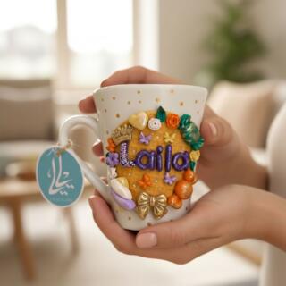 Handmade personalized clay mug with custom name decoration and colorful decorative elements.