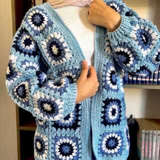 Handmade crochet cardigan in shades of light blue, navy, and white featuring circular floral-inspired patterns with a textured finish.