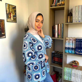 Handmade crochet cardigan in shades of light blue, navy, and white featuring circular floral-inspired patterns with a textured finish.