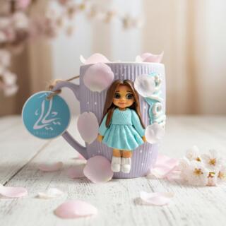 Lavender mug with a handmade polymer clay girl wearing a soft blue dress and personalized name detail.