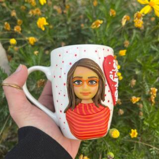 Handmade custom mug with a polymer clay portrait of a woman wearing glasses and a red striped top, decorated with red dots and a heart detail.