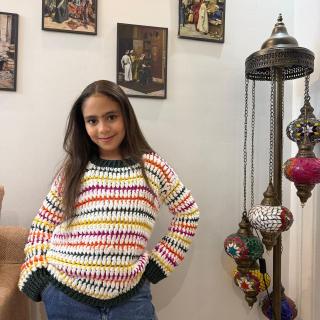Handmade chunky knitted sweater with colorful striped details, dark green cuffs, and a cozy oversized fit.