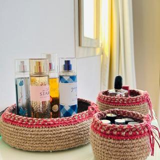 Set of handmade crochet storage baskets with decorative stitched edges and tie details, styled as organizers for perfumes, cosmetics, and small essentials.