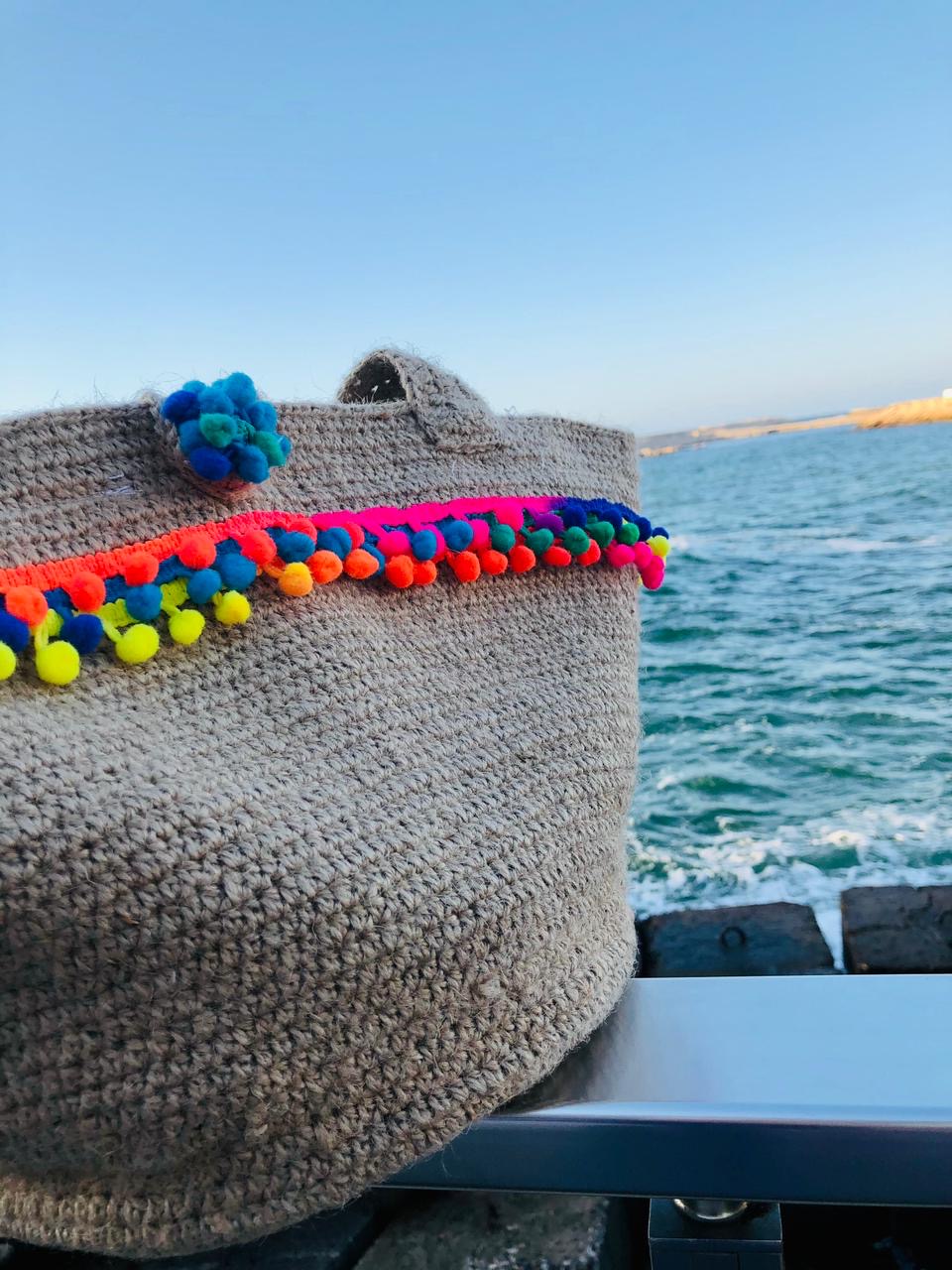 PomPom Jute Tote 1 Handmade jute crochet tote bag with colorful pom-pom trim and sturdy shoulder straps.