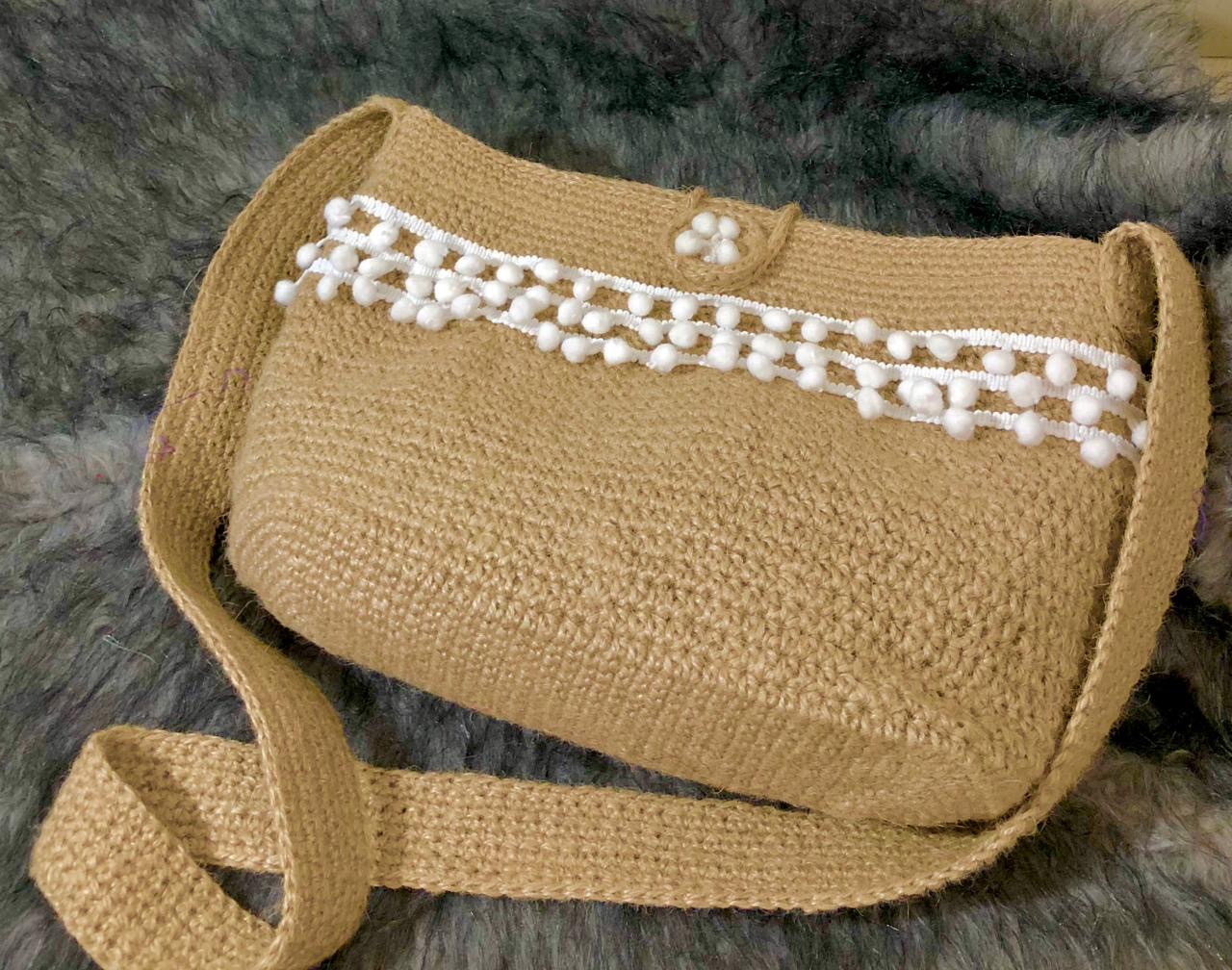 Pearl Pom Jute Tote 1 Handcrafted jute sling bag with white pom-pom trim, long woven strap, and soft checked fabric lining.